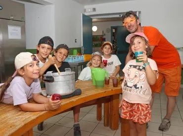 un groupe d'enfants et leur animateur mélangent dans une grande marmiter