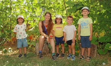 un groupe d'enfants et leur animatrice sont entourés de verdure