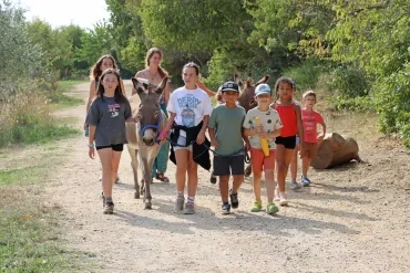 Un groupe d'enfants et leur animatrice tiennent deux ânes