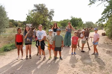 Un groupe d'enfants et leur animatrice tiennent deux ânes