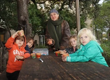 Un groupe d'enfants et leur animatrice montrent des petits pots en terre