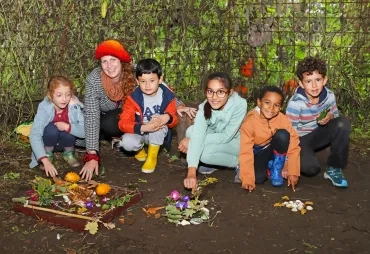 Un groupe d'enfants et leur animatrice installent au sol des éléments naturels