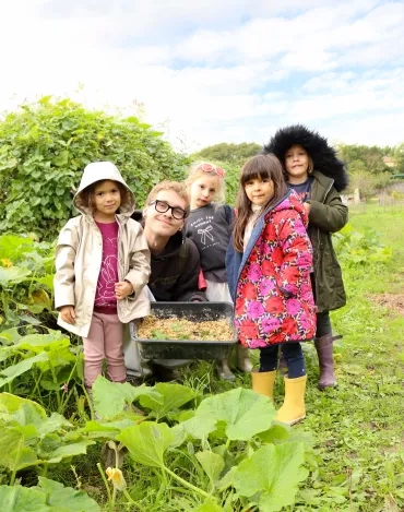 Un groupe d'enfants et leur animateur posent avec une gamelle de nourriture