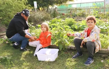 Deux enfant et leur animateur récolte des aubergines