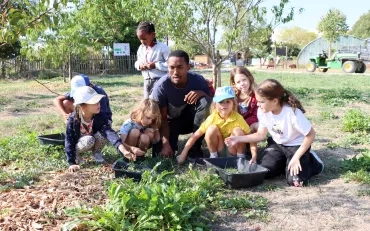Un groupe d'enfants et leur animateur ramassent de l'herbe