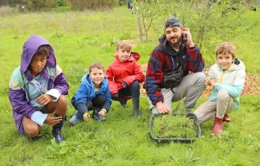 Un groupe d'enfants et leur animateur posent avec une bassine remplie d'herbe