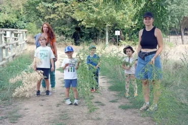 Un groupe d'enfants et leurs animatrices portent des branches