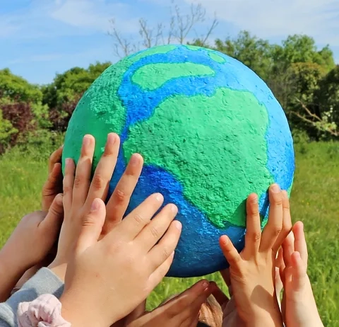 des mains d'enfants tiennent une planète en papier mâché