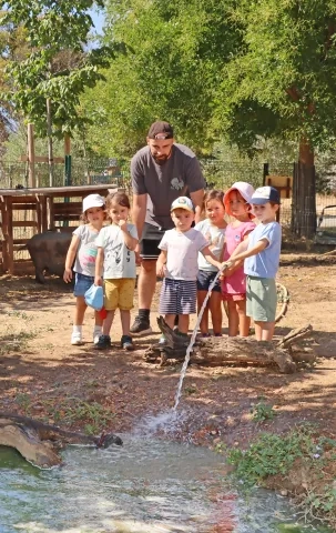 un groupe d'enfants et leur animateur arrosent une mare