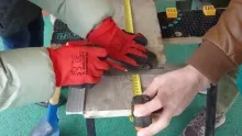 Deux adultes mesurent et tracent sur une planche en bois