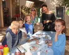 un groupe d'enfants et leurs animatrices montrent des branches peintes