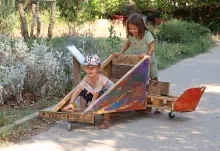 deux enfants sont dans une voiturette en bois