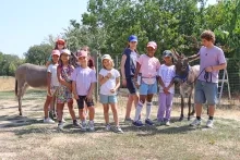 un groupe d'enfants et leur animateur posent avec deux ânes