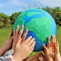 des mains d'enfants tiennent une planète Terre en papier maché