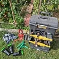 Photo d'outils de jardinage avec une malle disposés devant un potager