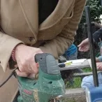 une adulte coupe une plante avec une scie sauteuse