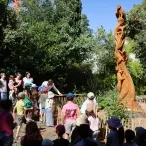 un groupe d'enfant et d'adulltes sont prêts d'une statue en bois