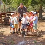un groupe d'enfants et leur animateur arrosent une mare