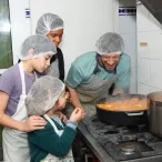 Un groupe d'enfants et leur animateur sont en cuisine autour d'une grosse marmite de soupe