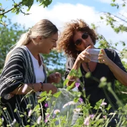 Photo de deux personnes dans la nature entrain d'oberserver un insecte dans une petie boîte loupe